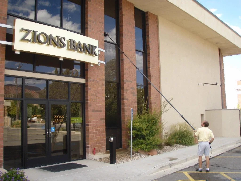 Busy B technician using a water-fed pole on commercial exterior windows
