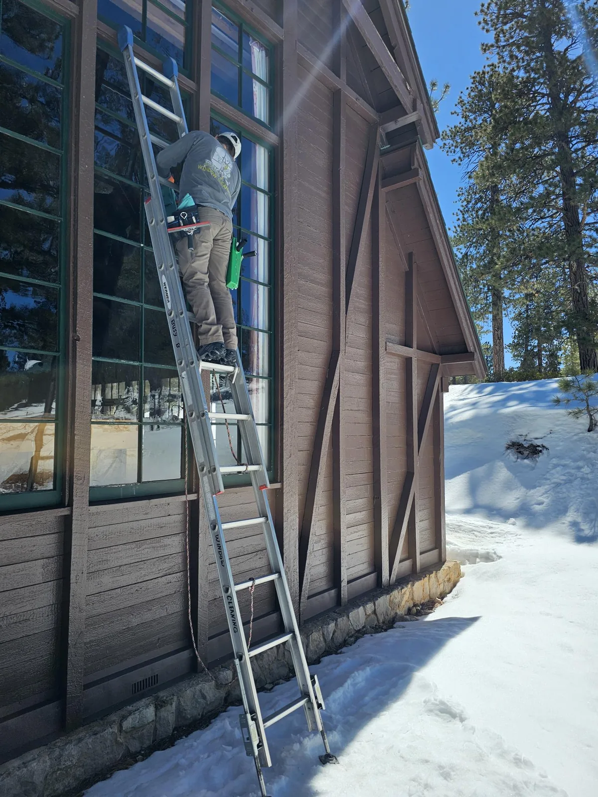 Extension-ladder work on tall windows in the snow.