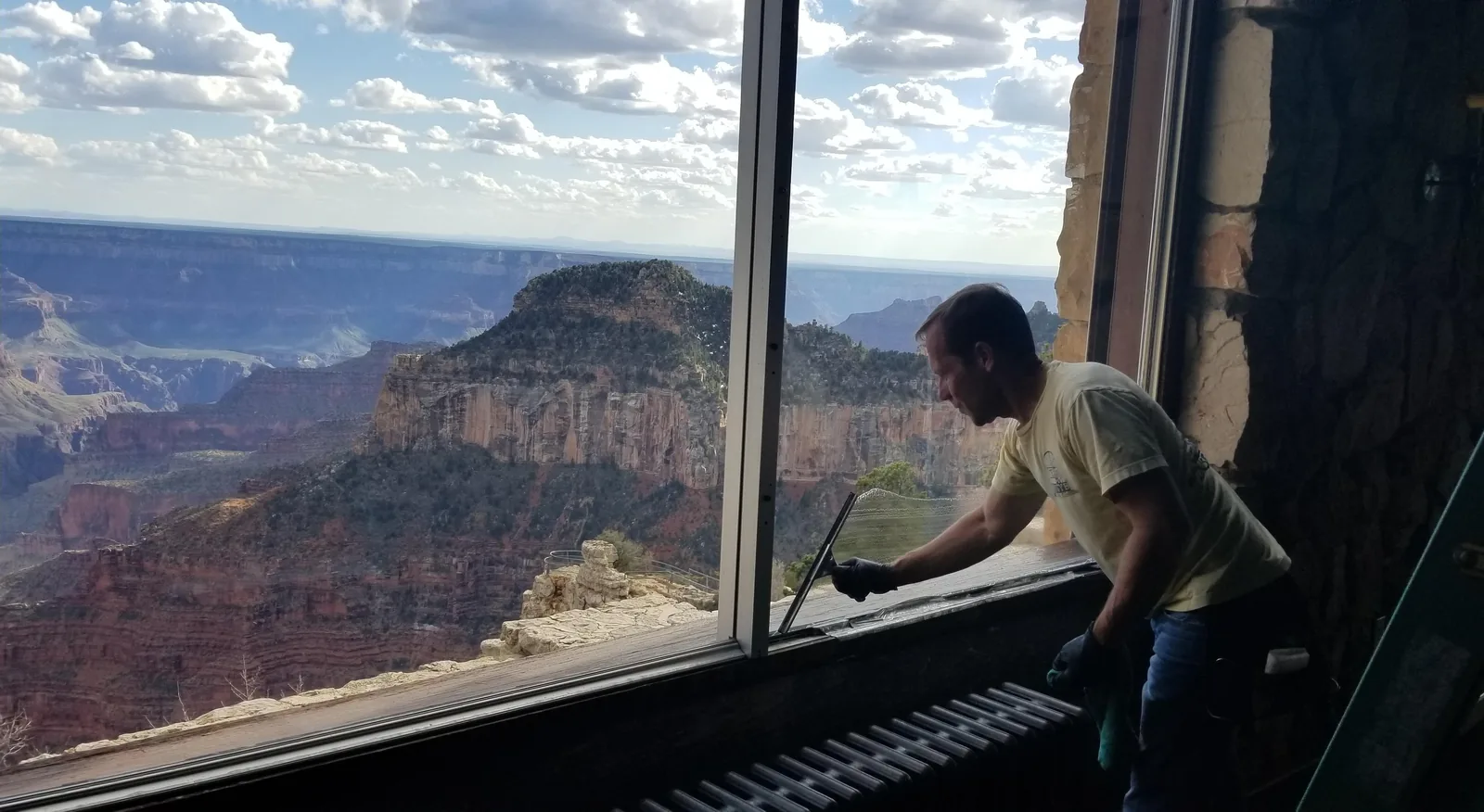 Jim cleaning a lodge window that looks out over the Grand Canyon