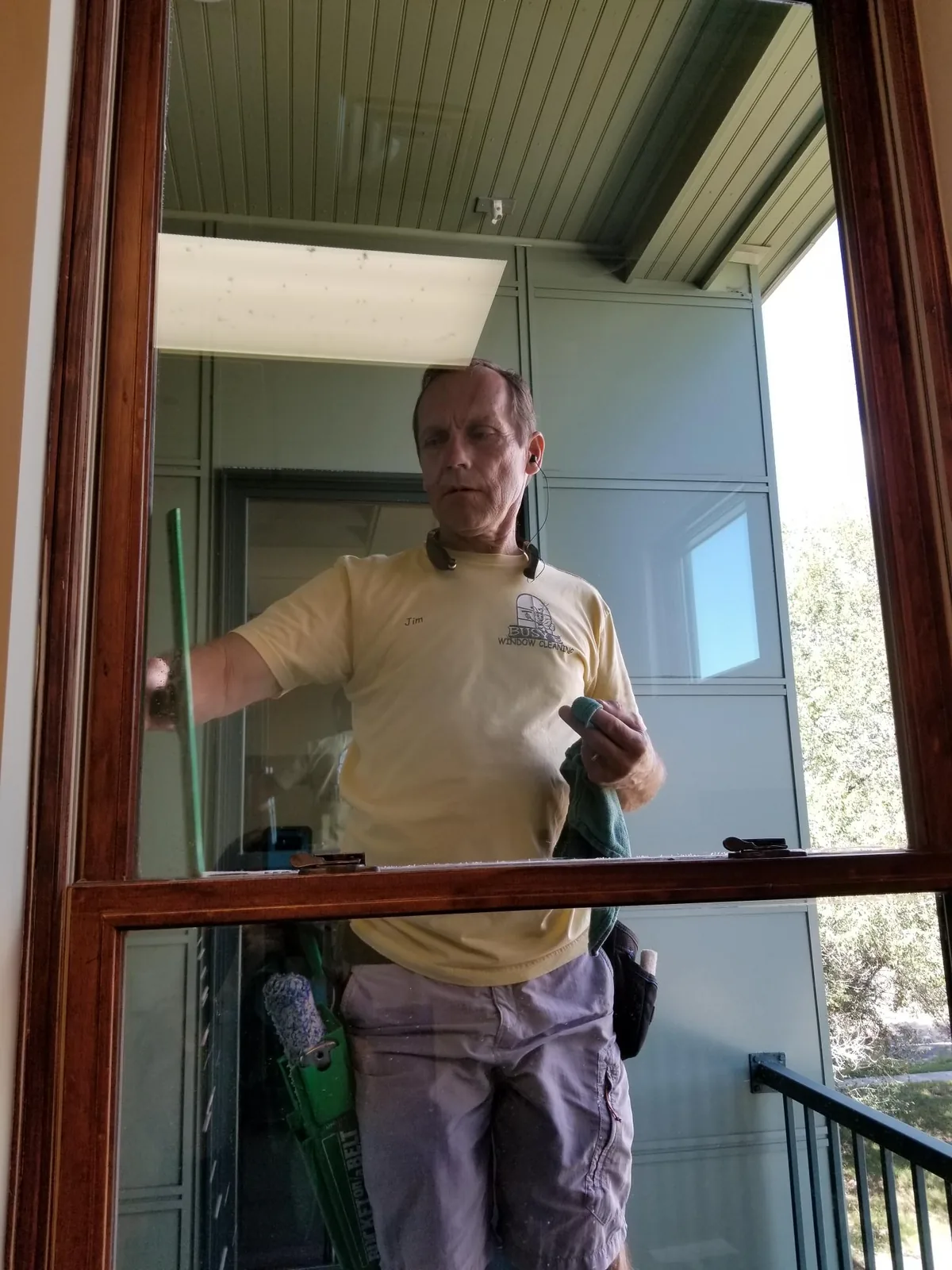 Jim cleaning interior glass beside a balcony.