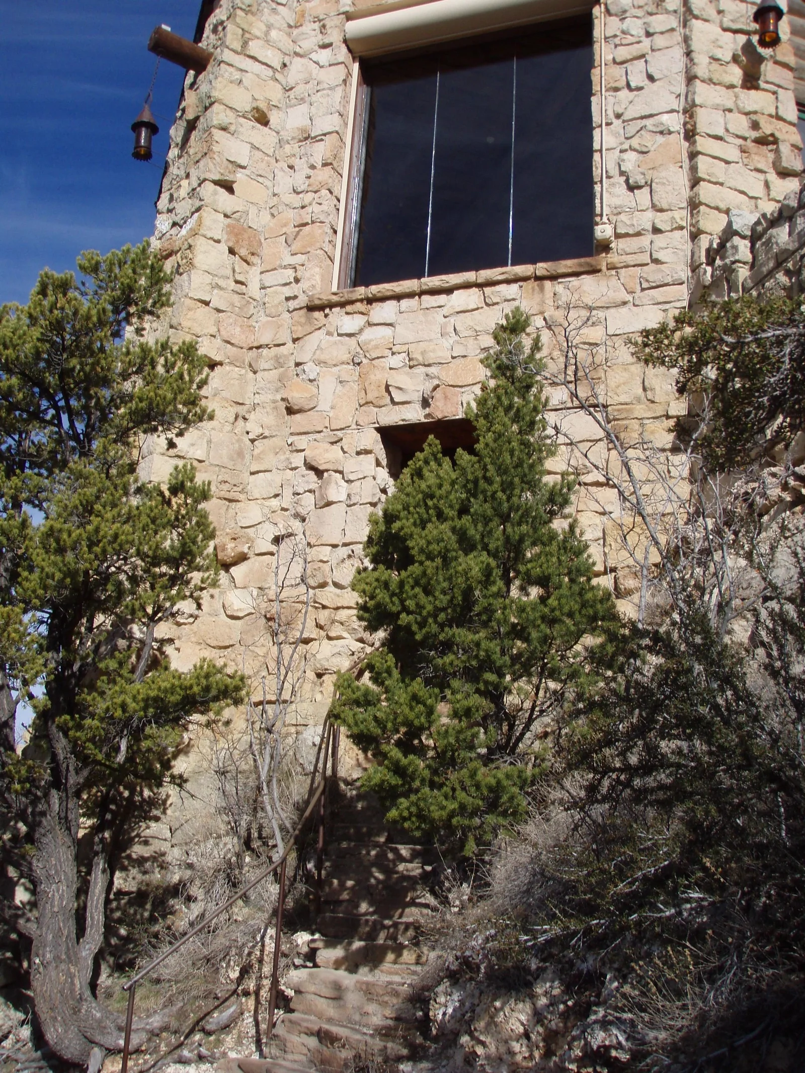 Cleaning a tall window in a stone exterior.