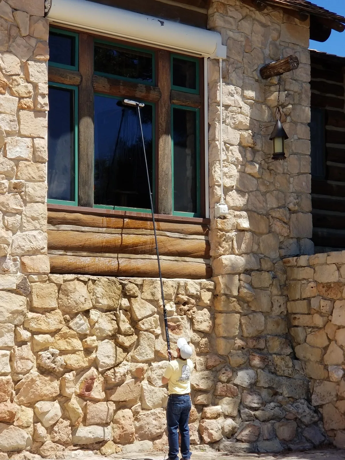 The water-fed pole reaching a window above a stone wall.