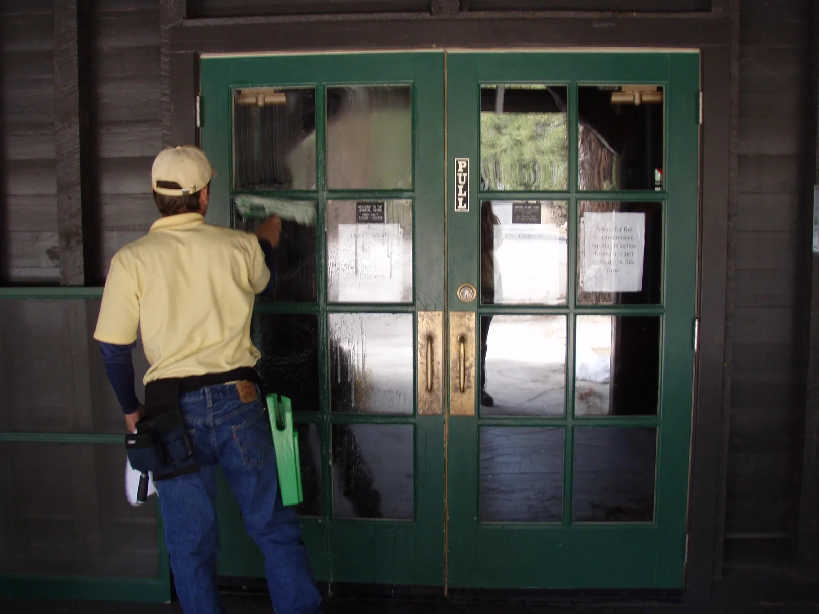 Busy B technician cleaning wood-framed entry windows